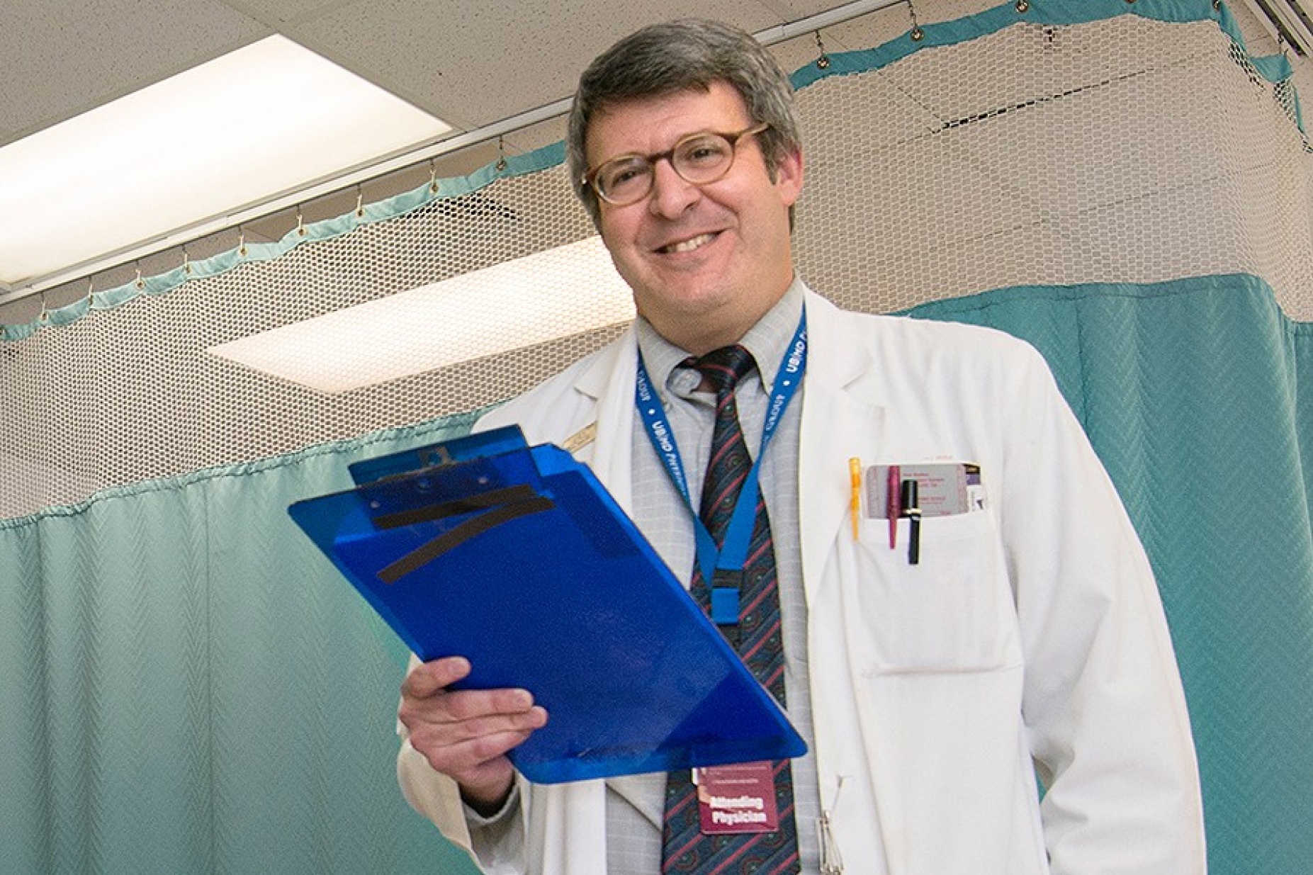 Gil Wolfe in white coat, holding clipboard.