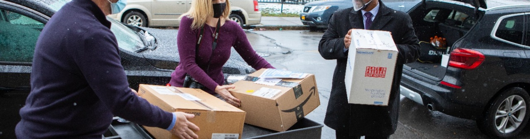 L to R Michael O'Hara and Heather Mattiuzzi of the Buffalo City Mission receive boxes from Praveen Arany.
