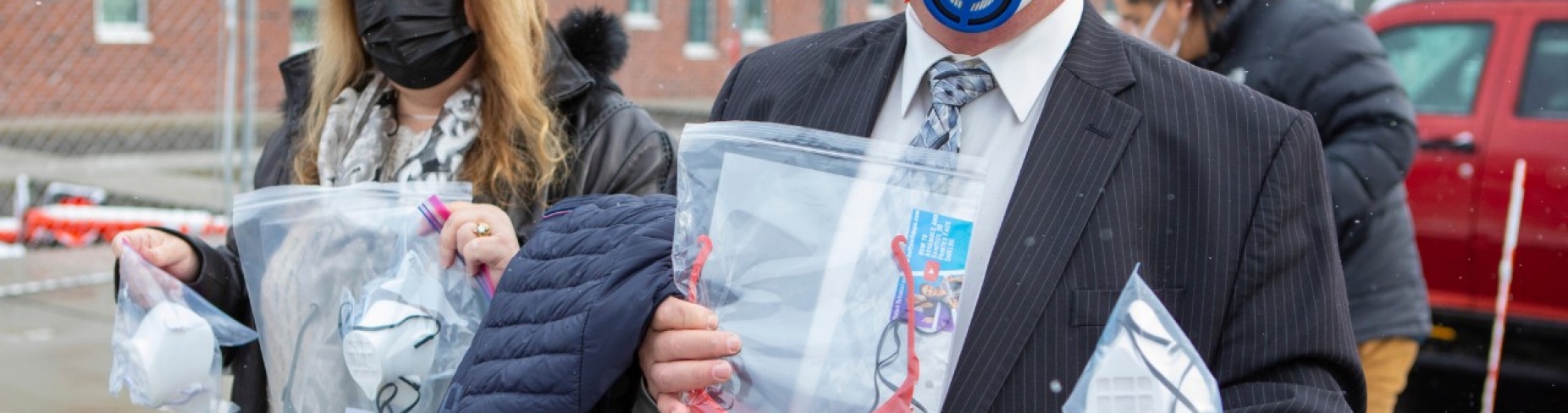 L to R: Marge and Peter Elkin hold masks and shields and Philip Sales is in background.