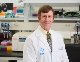Bruce Troen in white coat in lab. 