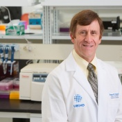 Bruce Troen in white coat in lab. 