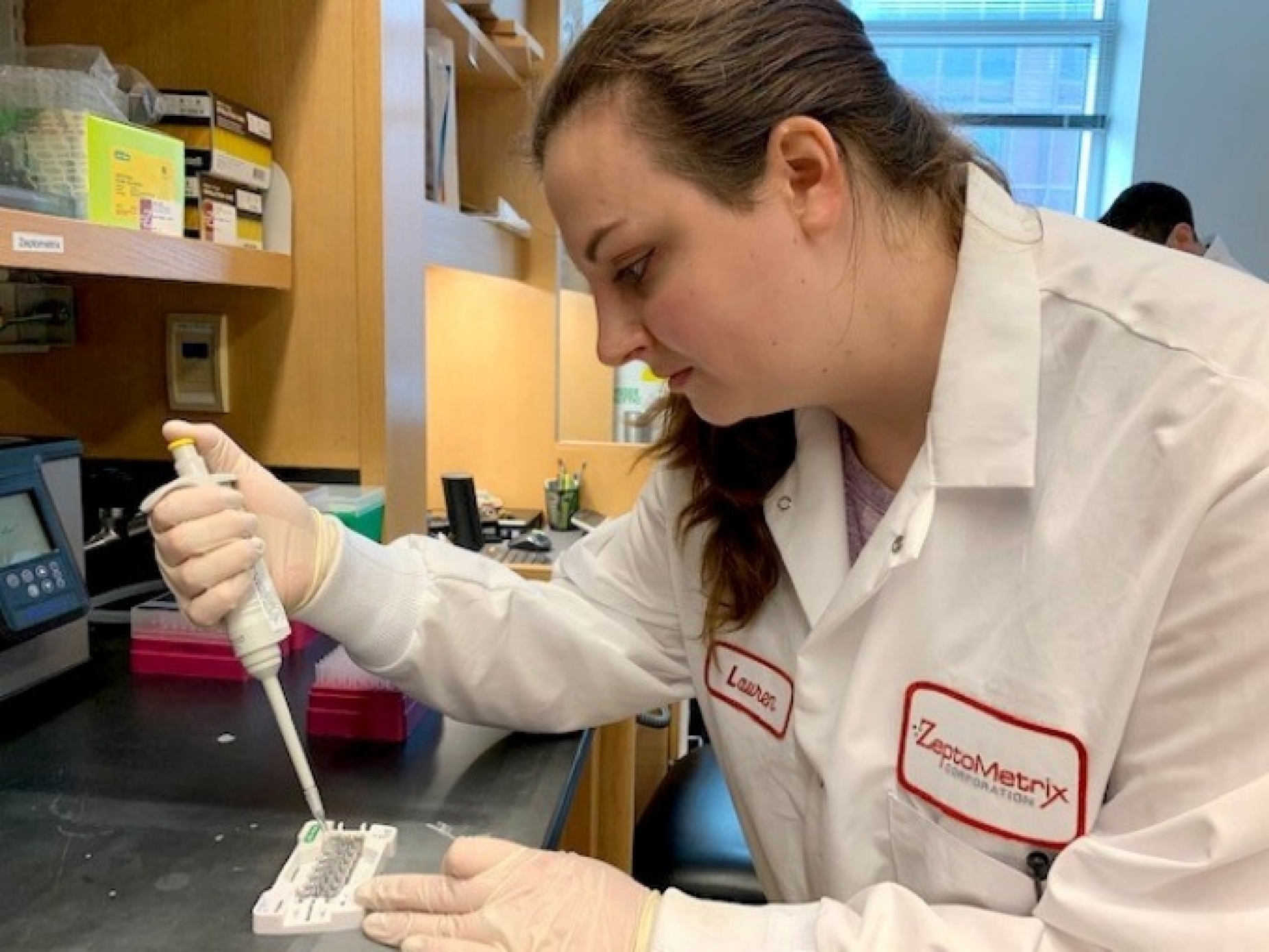 ZeptoMetrix molecular biologist Lauren Morrow loads reagents into a cartridge used in a digital droplet PCR platform with an automated droplet generator. Photo: Karuna Sharma. 