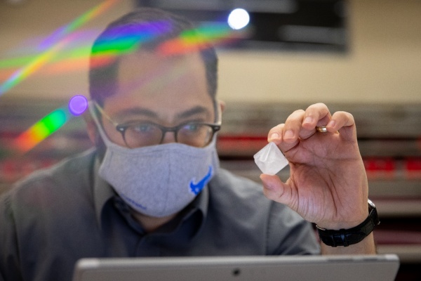 Zoom image: Luis Velarde, UB associate professor of chemistry and a repeat judge, examines a crystal. Credit: Meredith Forrest Kulwicki. Additional photos of the crystal contest judging are available for download. 