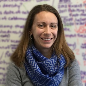 Kristin Poinar standing in front of a white board. 