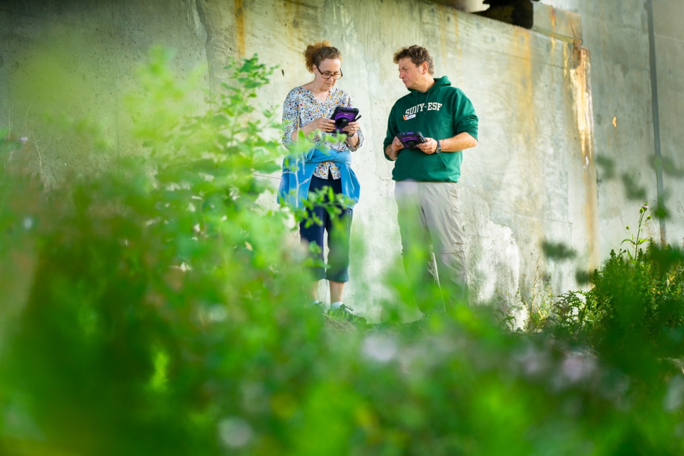 Zoom image: From left: Sara Rockwood-Klute, biology and earth sciences teacher at Eden High School, and Paul Parrinello, chemistry and earth sciences teacher at Depew High School, examine information on a tablet. Credit: Douglas Levere / University at Buffalo 