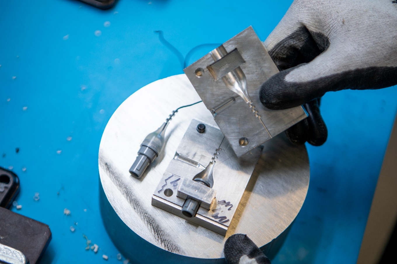 Zoom image: Garwood Medical Devices will use injection molding, which injects molten plastic into a cavity, to produce and connect parts for its BioPrax&trade; device. In this photo, two halves of a metal mold are shown, with the finished part (a connector) lying to the left. Credit: Douglas Levere / University at Buffalo 