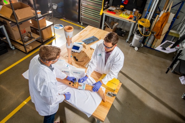 Zoom image: Garwood Medical Devices&rsquo; Tim Kopera, engineering manager, and Jackson Hobble, biomedical engineer and a UB alumus, demonstrate the BioPrax&trade; technology. BioPrax&trade; is being developed to treat biofilm infections on prosthetic knee implants during early intervention procedures and used alongside the current standard of care. The device, which is currently undergoing pre-clinical development, provides a low-voltage electrical signal to prosthetics, creating an electrochemical reaction that kills bacteria associated with biofilms. Credit: Douglas Levere / University at Buffalo 