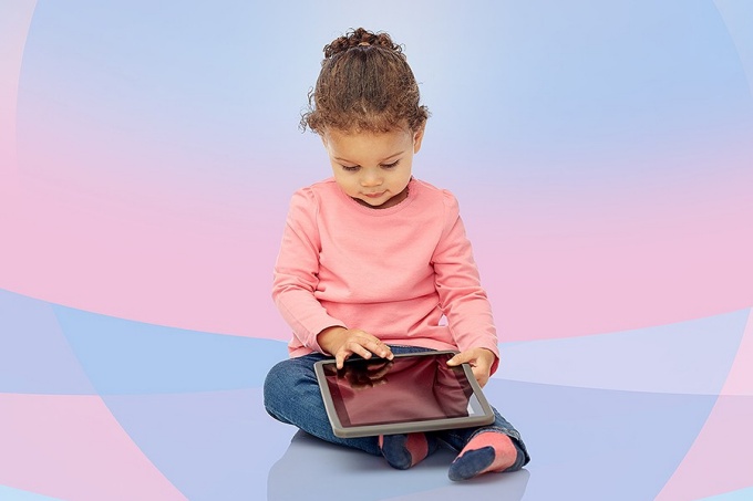 Young child sitting down using tablet. 