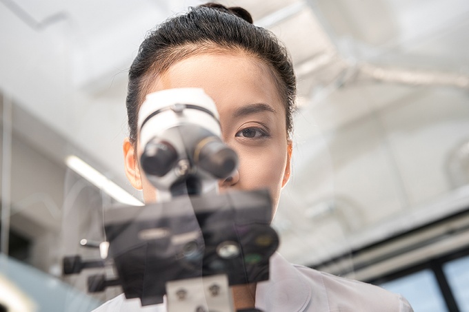 A woman looking through a microscope. 