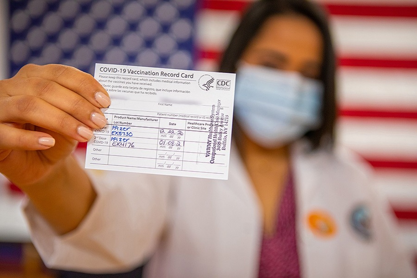 Photo of a vaccinated student holding up their COVID-19 vaccine card (with personal information blurred out). 