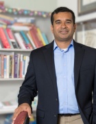 Sourav Sengupta standing in office in front of bookshelves. 