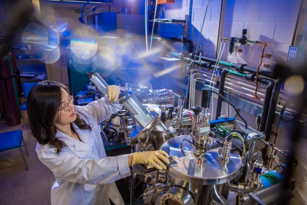Zoom image: UB physics postdoctoral researcher Mengying Bian works with a dual chamber thin film deposition system. Credit: Douglas Levere / University at Buffalo 