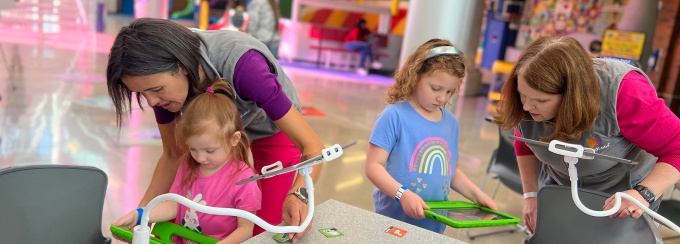 Two adults teach two students how to use MindLabs, a platform for teaching young students STEM-based concepts in fun and engaging ways. 