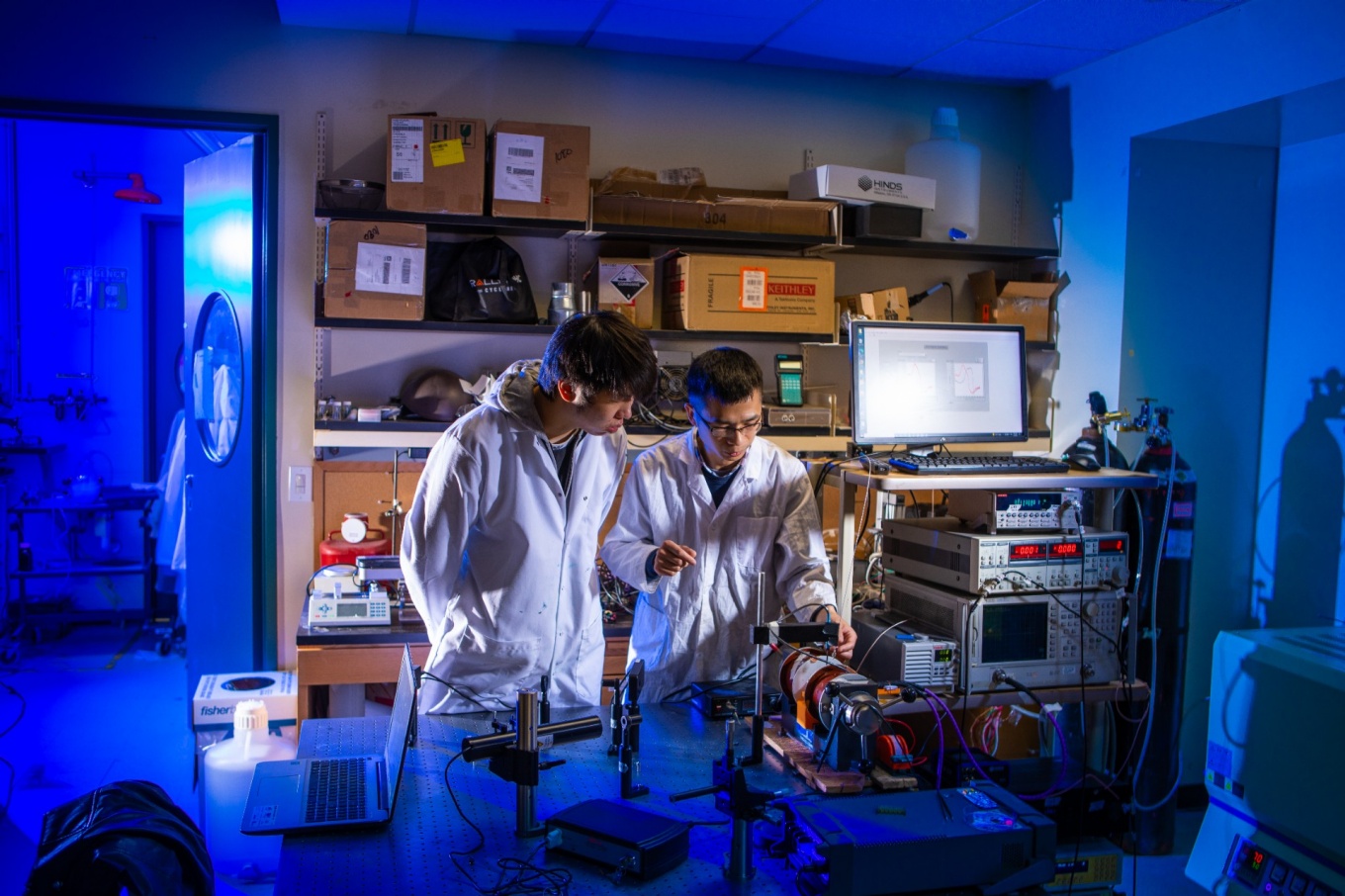 Zoom image: From left: Zheng Li and Yulong Huang demonstrate a system for measuring the magnetism of a magneto-ionic material used in a rechargeable lithium-ion battery. Li and Huang, both UB postdoctoral researchers in mechanical and aerospace engineering, are among authors of a new study on the material. Credit: Douglas Levere / University at Buffalo 
