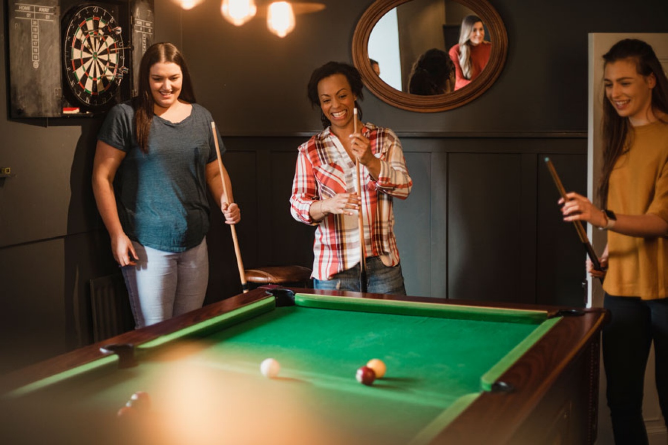 Three women playing a game of pool. 