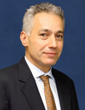 Portrait of man wearing a dark suit and patterned tie. 