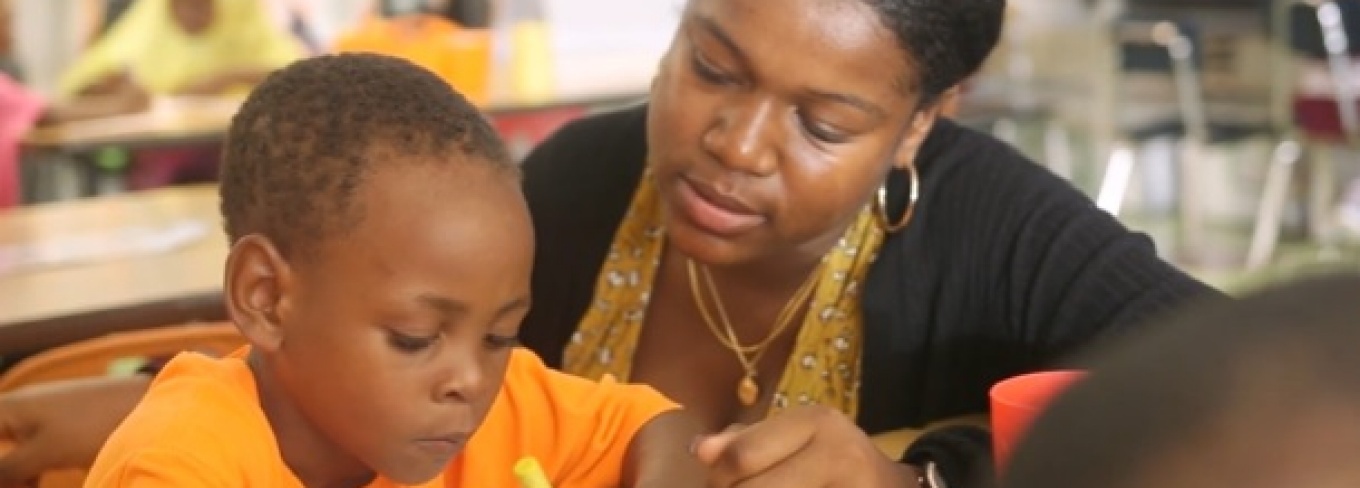 Teacher resident working with student at a desk.