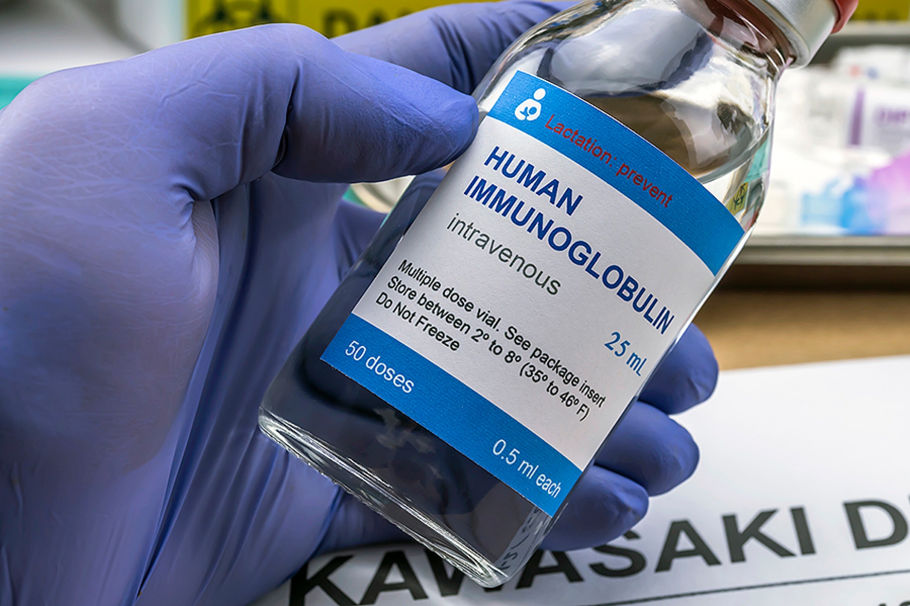 A gloved hand holding a vial of human immunoglobulin, a treatment for Kawasaki disease. 