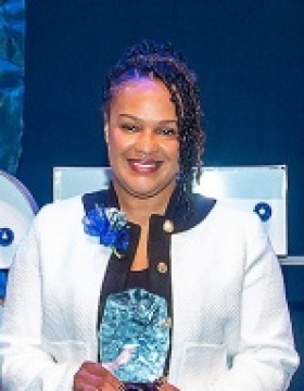 Christian Johnson stands with her award on stage at Fast 46. 