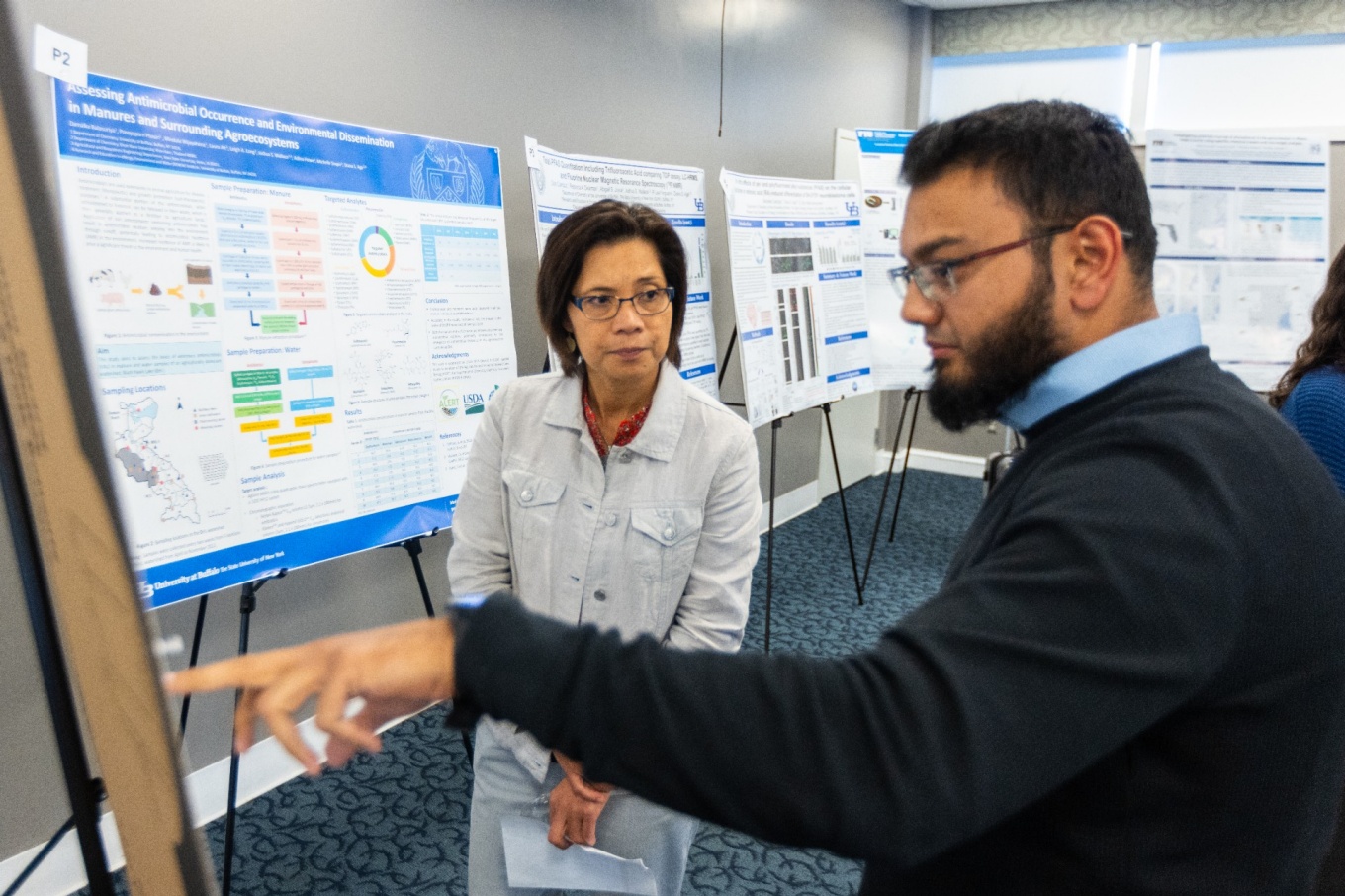 Zoom image: Diana Aga, director of the UB RENEW Institute, examines research posters as part of the workshop Sept. 25 in the UB Center for Tomorrow. Photo: Douglas Levere/University at Buffalo 