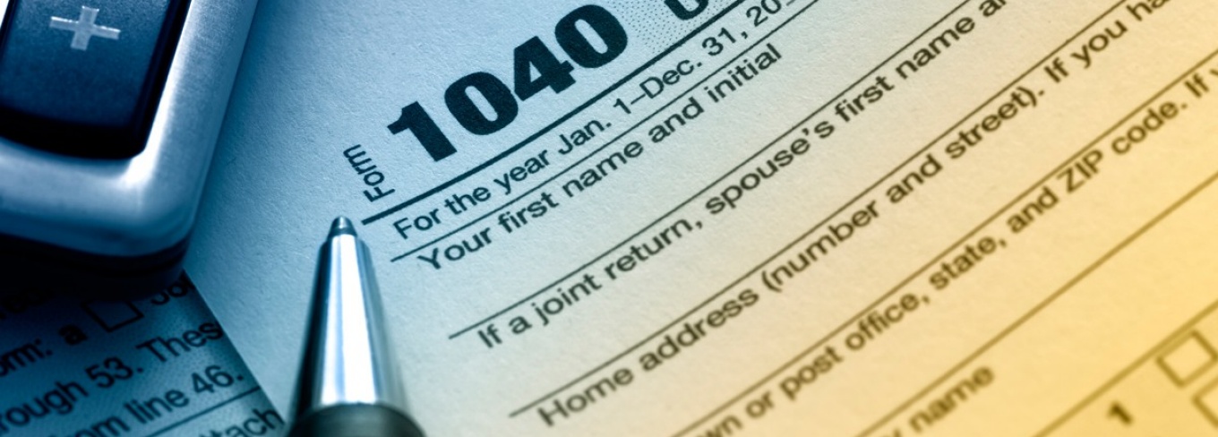 Part of tax form 1040 with the tip of a pen and part of a calculator. 