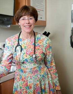 Kim Griswold is standing in an exam room, there is a stethoscope around her neck. 