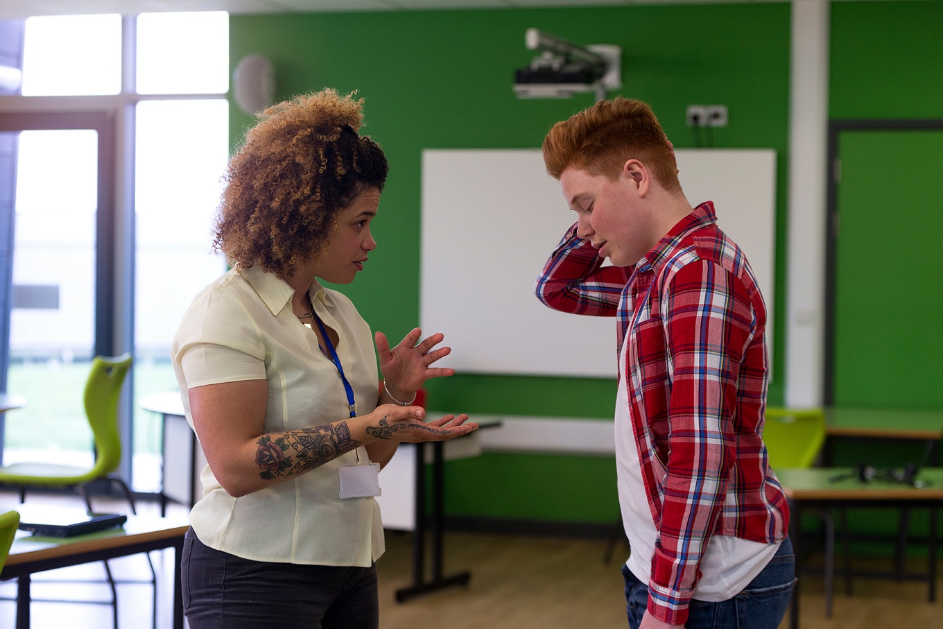 A high school teacher speaks sternly with an uneasy student. 