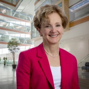 Allison Brashear, wearing a red blazer, is in the medical school atrium. 