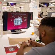 An instructor holding a mic lectures a dental class. 