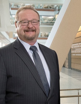 Peter Elkin is standing in the atrium of the Jacobs School. 