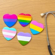 Concept of gender-affirming care featuring a stethoscope and hearts in gender flag colors. 