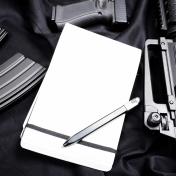 Guns and ammunition surrounding a notepad and pen. 
