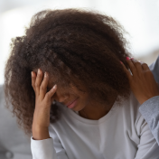 A younger Black woman being comfortaed by an adult. 