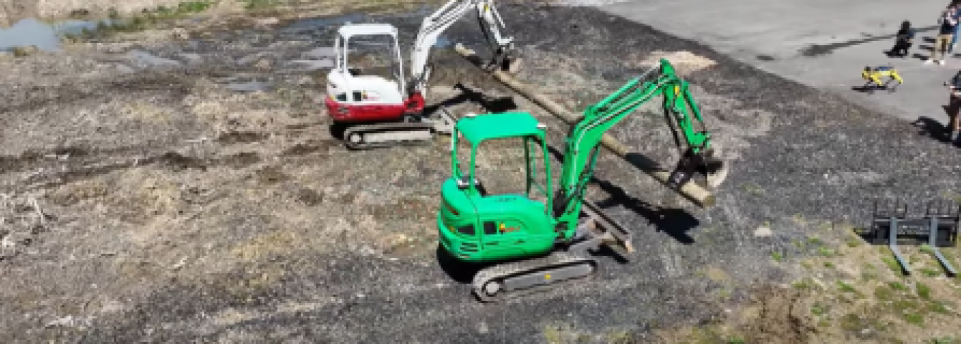 Two excavators work in a field. 