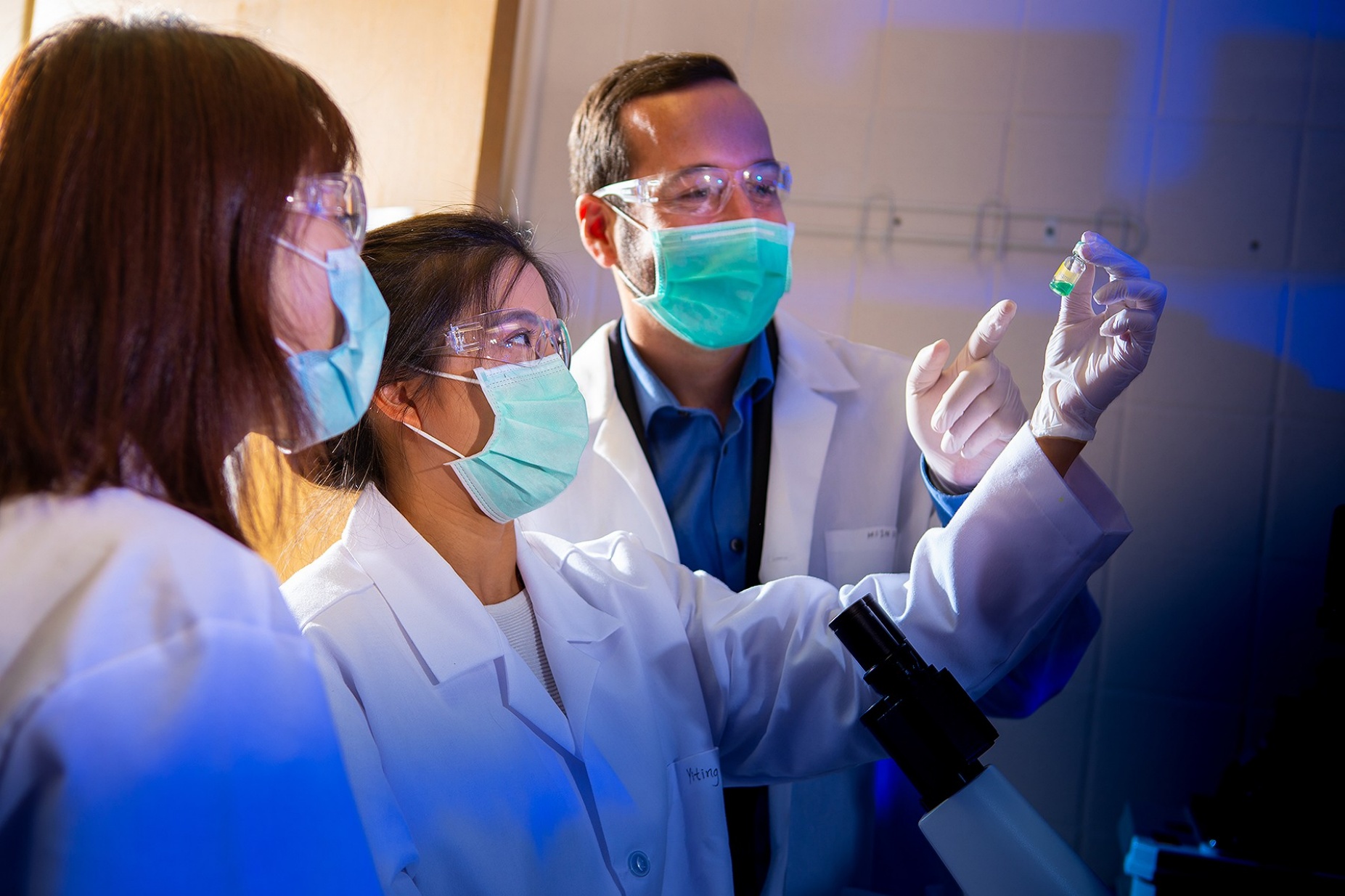 Three UB researchers work in a science lab. 