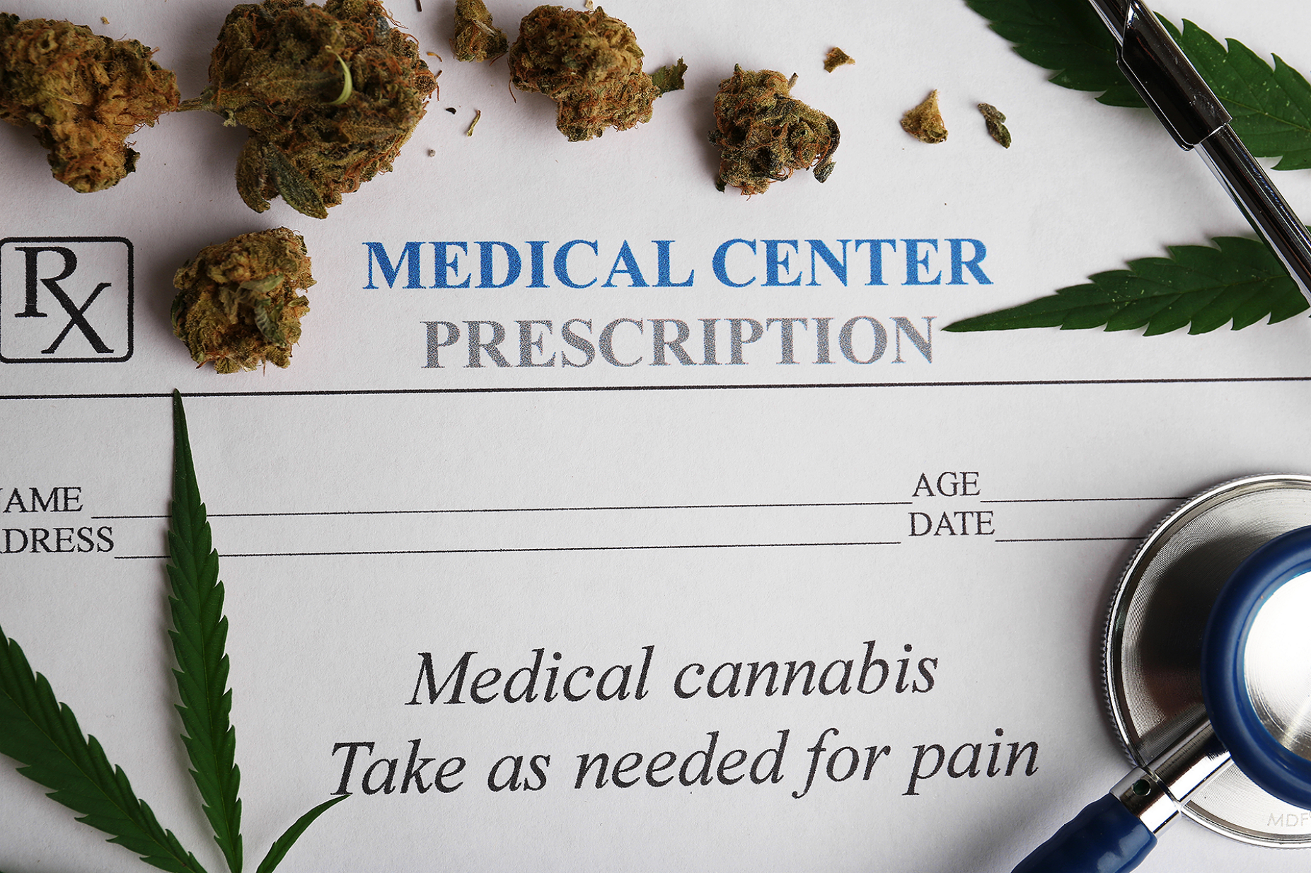 Concept of cannabis used for pain management featuring a prescription pad, stethoscope and dried cannibis buds.