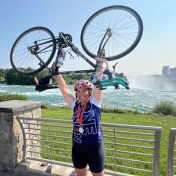 Emily Genovesi holding her bike above her head at Niagara Fall, NY. 