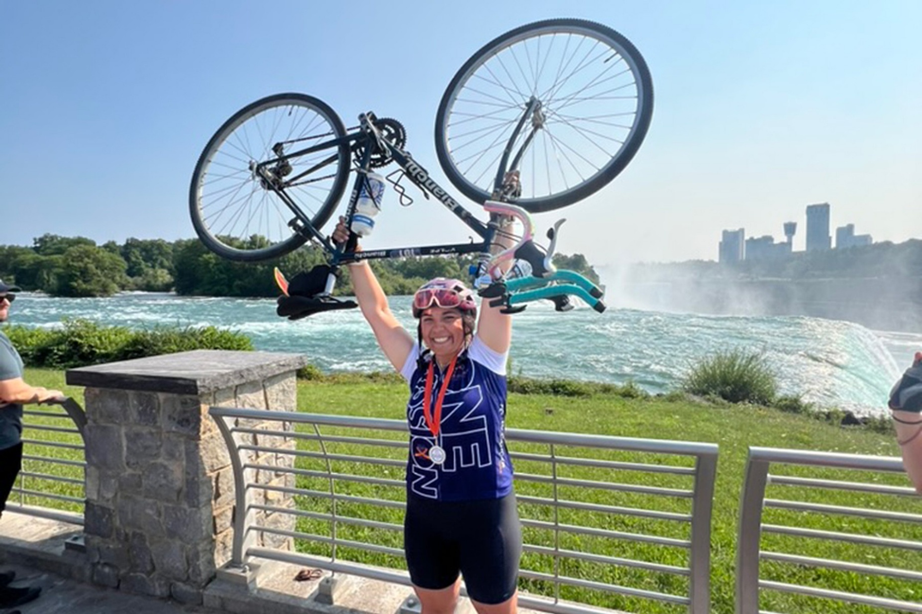 Emily Genovesi holding her bike above her head at Niagara Fall, NY.