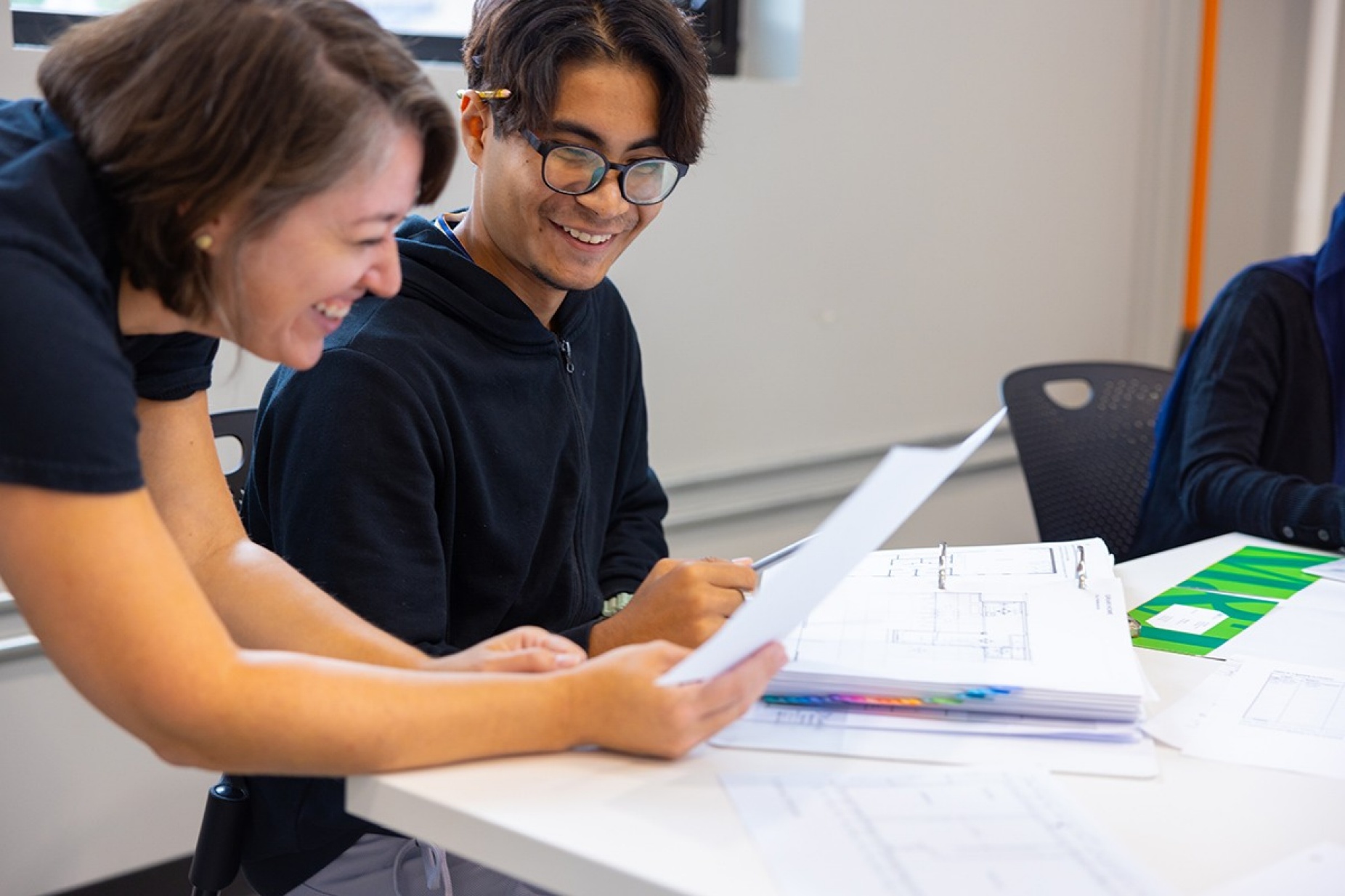 Female instructor and a male student smiling. 