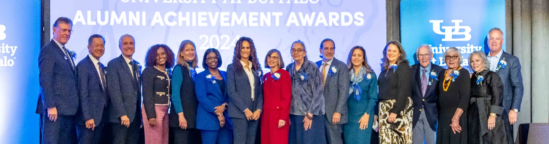 About 20 UB alumni stand together onstage at the Forbes Theater in Buffalo. 