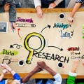 Image of people sitting at a big table collaborating on research ideas and topics. 