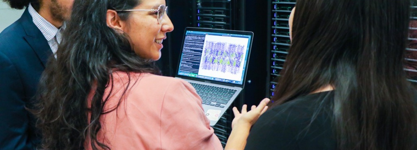 Viviana Monje (center) is surrounded by two students as they look at a computer. 