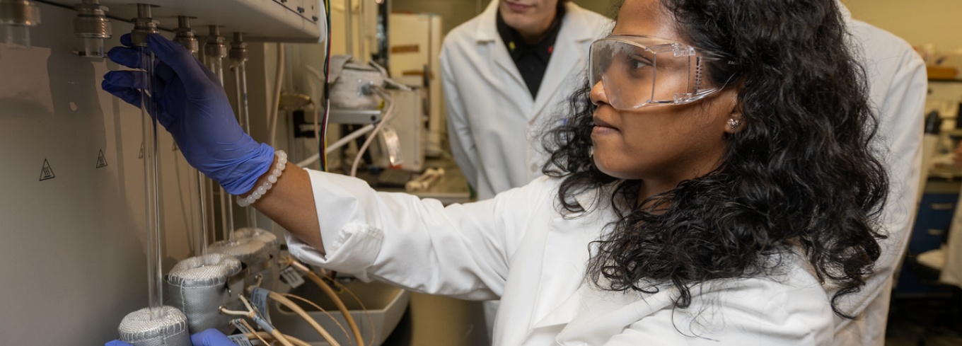 Three students in Miao Yu's lab work equipment to test the metal membranes they're working on.