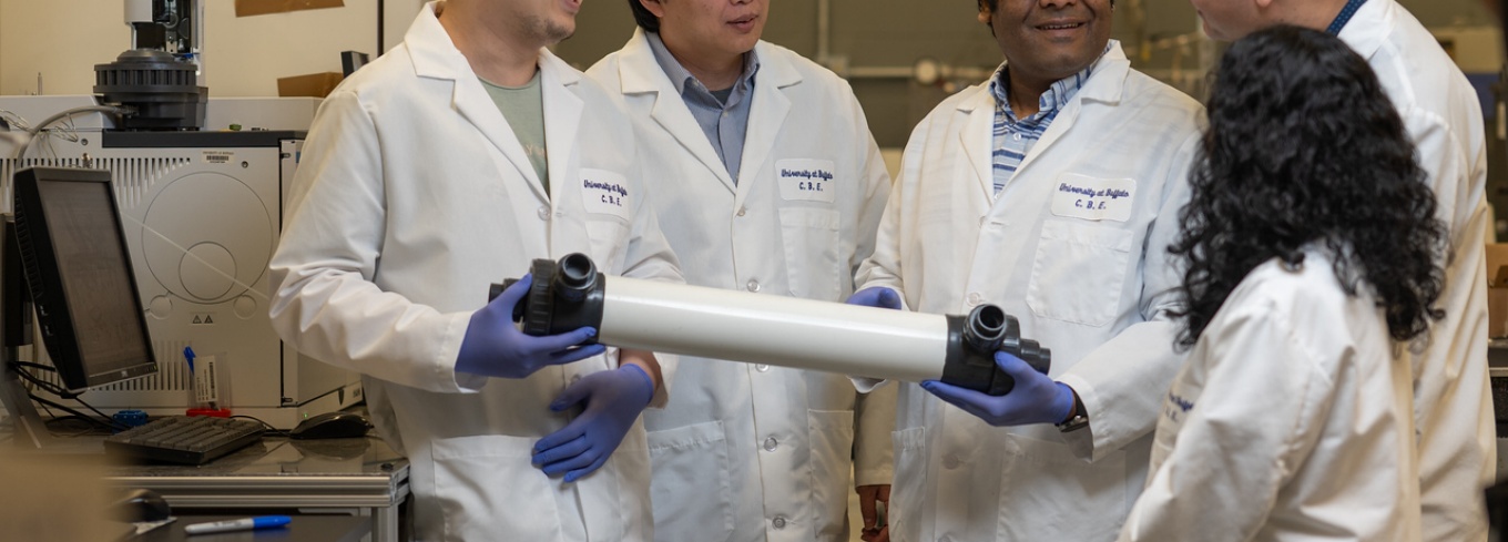 Miao Yu and three students in the lab holding a plastic tube.