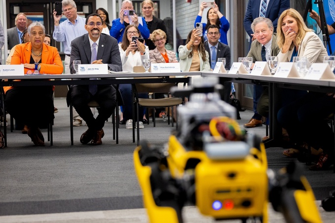 Zoom image: UB hosted an AI roundtable discussion in Lockwood Memorial Library in July 2024 that included faculty and students sharing the innovative work of UB researchers with SUNY Chancellor John B. King Jr. and state lawmakers. The crows responds to UB's robot dog, Yubie. Photo: Meredith Forrest Kulwicki 