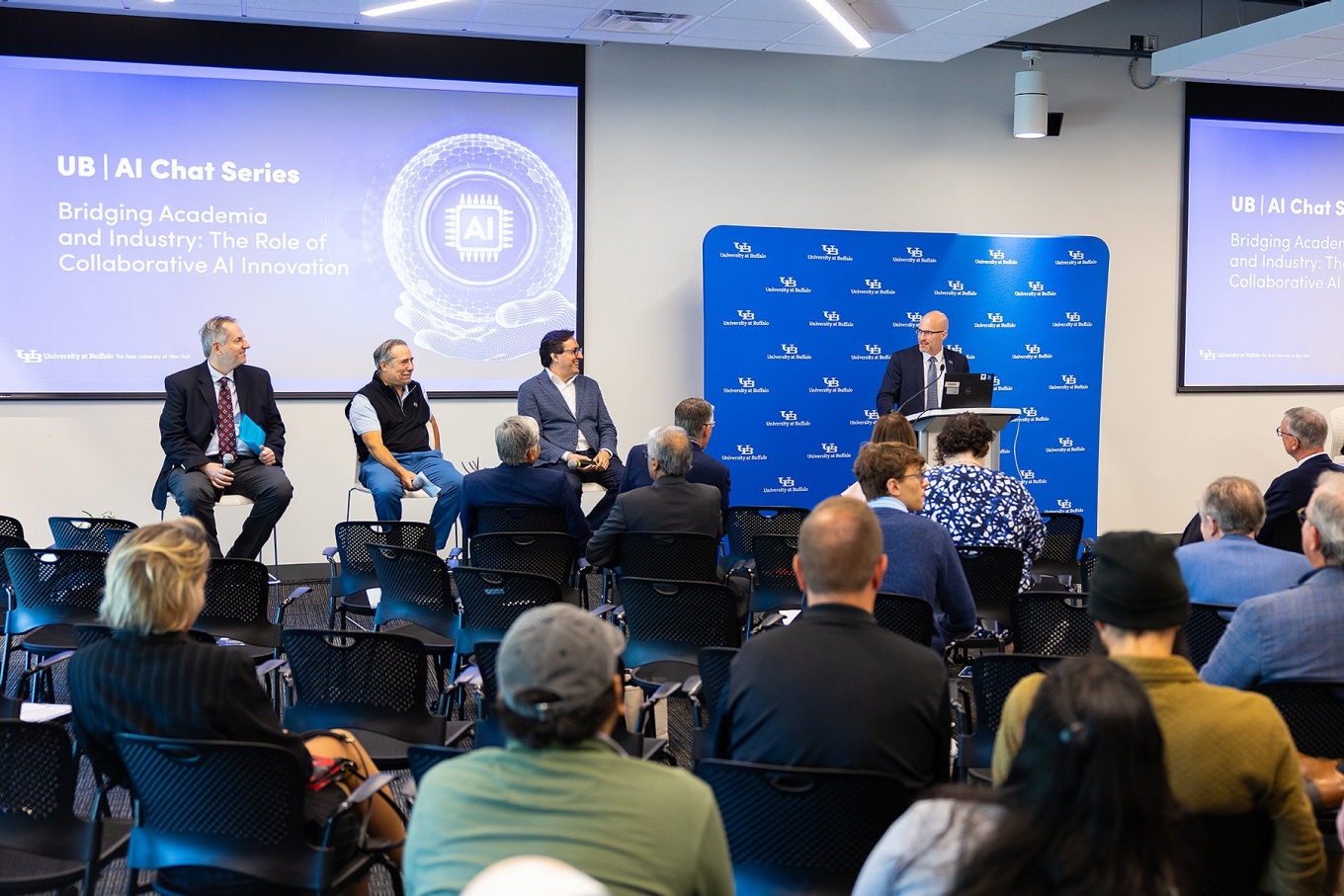 Zoom image: UB engineering dean Kemper Lewis (far right, at the podium) moderates a panel of industry leaders that includes (from left) Jose Pinto, Chris Tolomeo and Dario Gil. Photo: Douglas Levere 