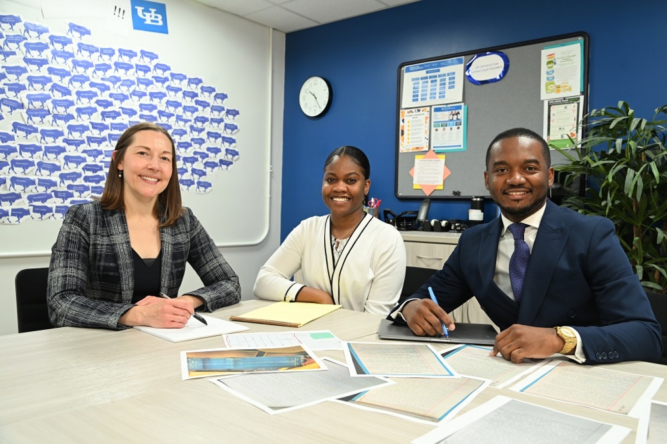 From left to right, Heather Abraham, Khalia Muir and Chris Flynn sit at a table with paperwork in front of them. 