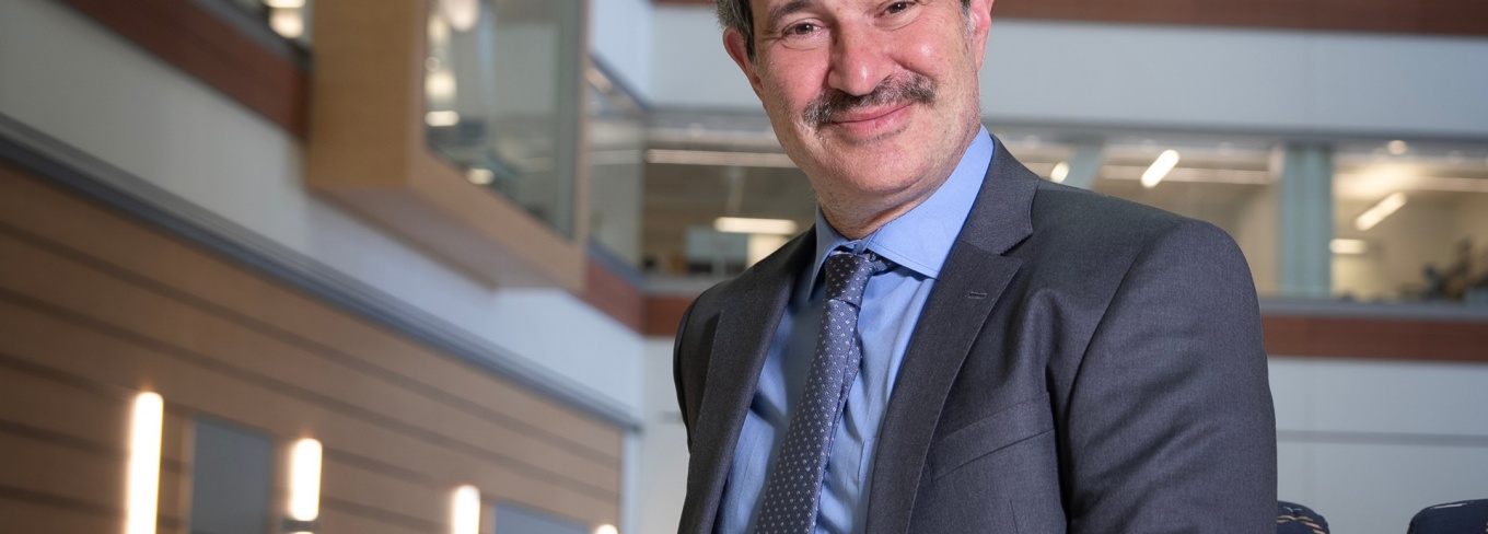 Andrew Talal, MD, is standing in the medical school atrium wearing a jacket and tie. 