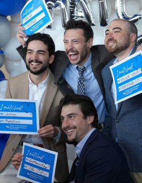 Four men with their match signs in front of the balloons. 