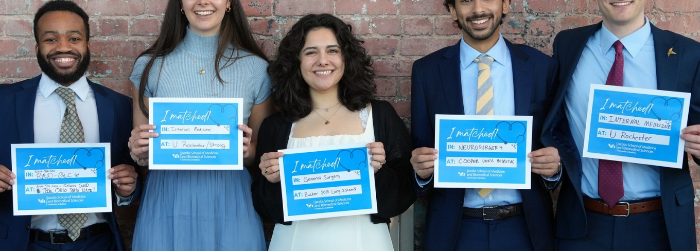 Five Jacobs School students hold their I matched at signs in front of brick wall.